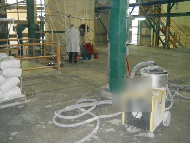 Industrijska hala sa usisnom mašinom i razvučenim crevima po podu.